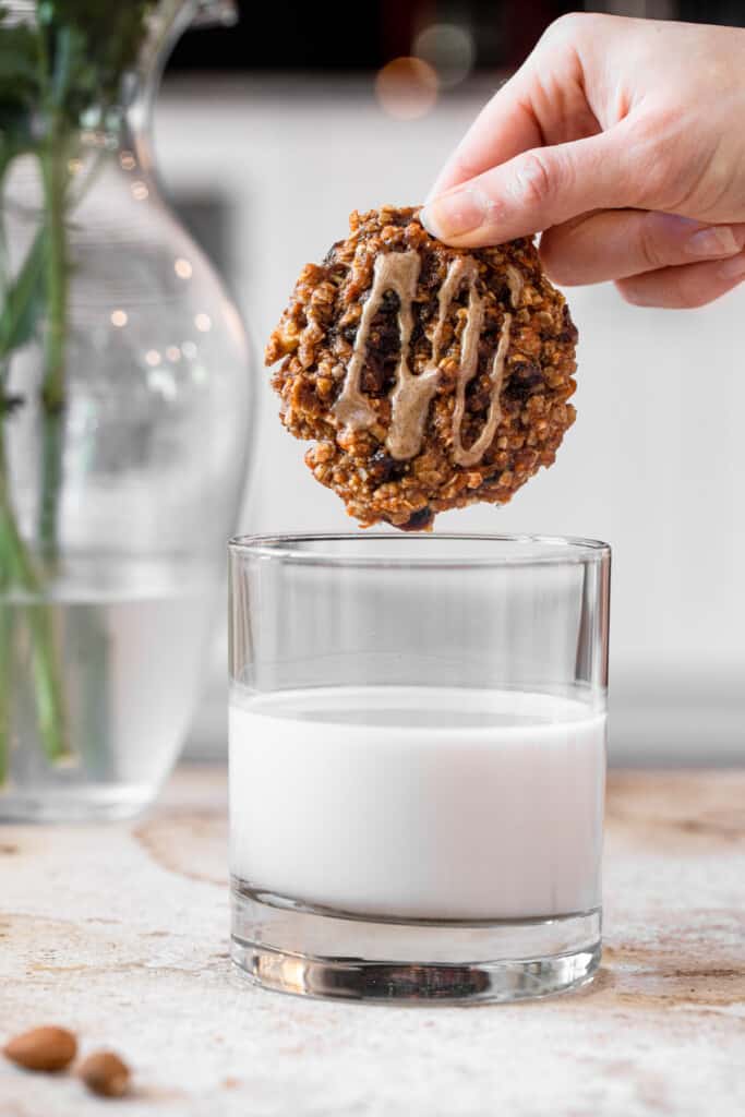 sweet potato cookie being dipped into a short glass of milk