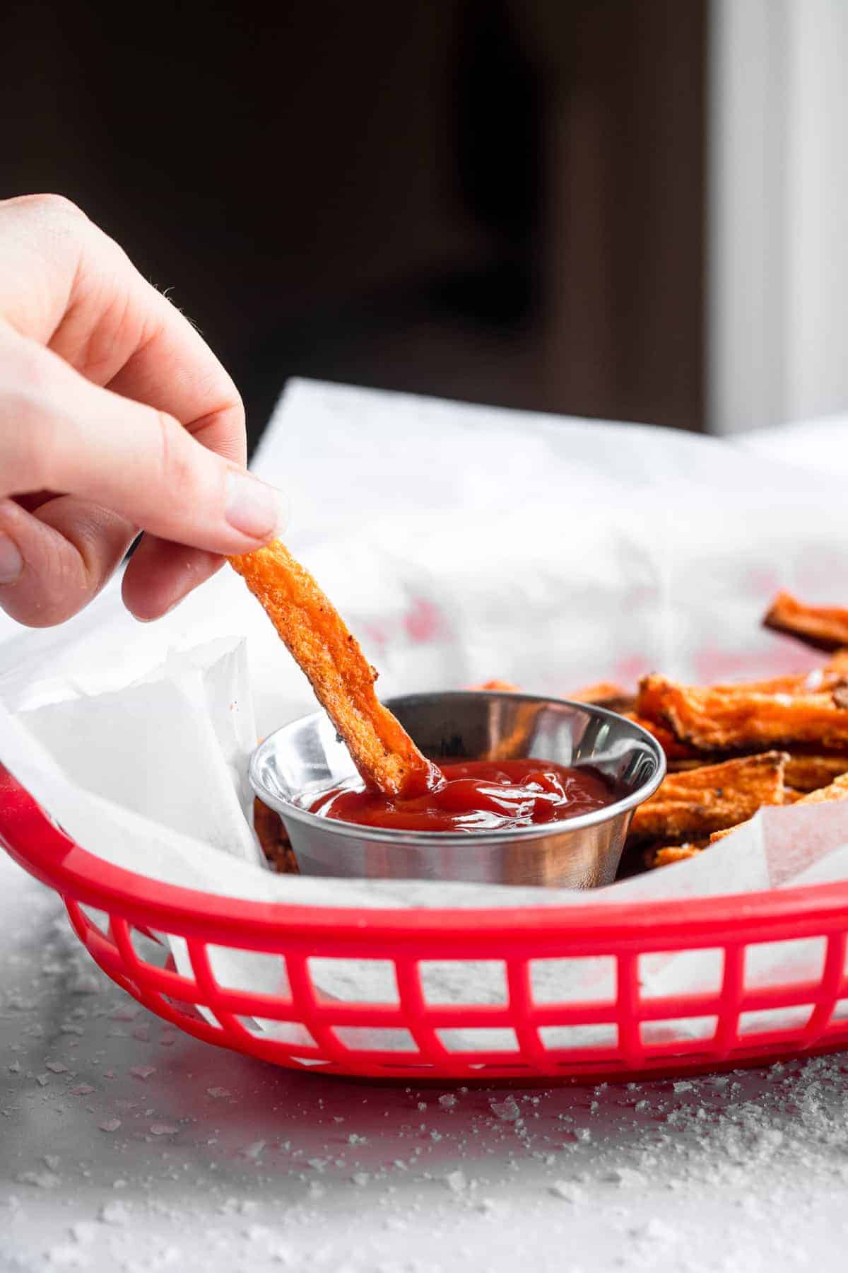 baked sweet potato fries in a serving basket with ketchup