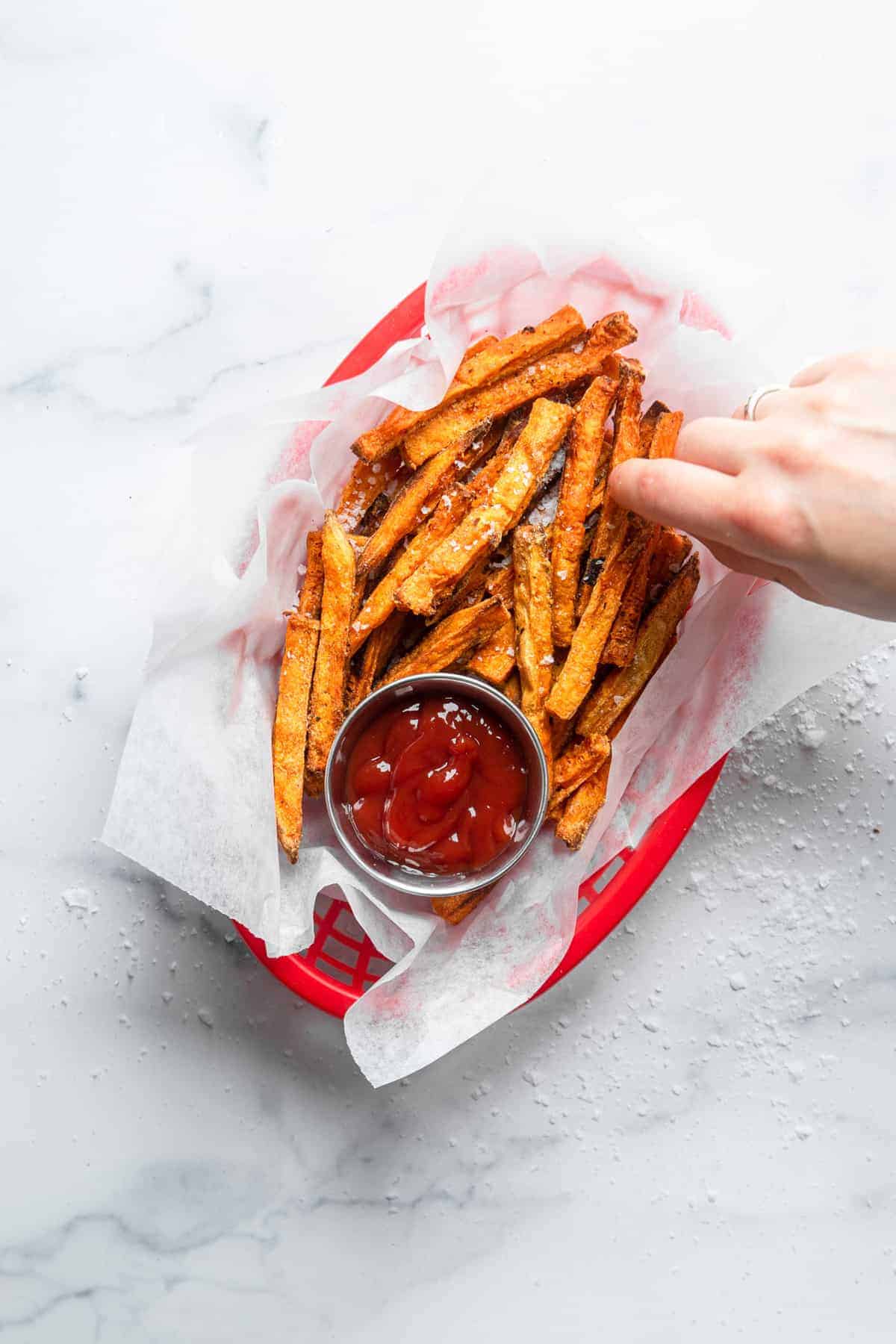 top view of bakes sweet potato fries in a basket with ketchup