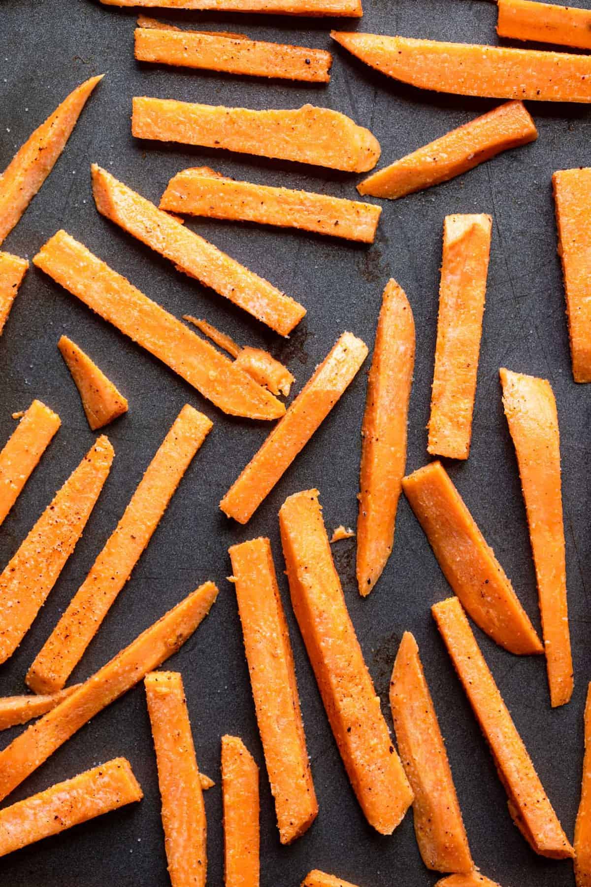 sweet potatos sliced on a baking sheet ready to be cooked for baked sweet potato fries