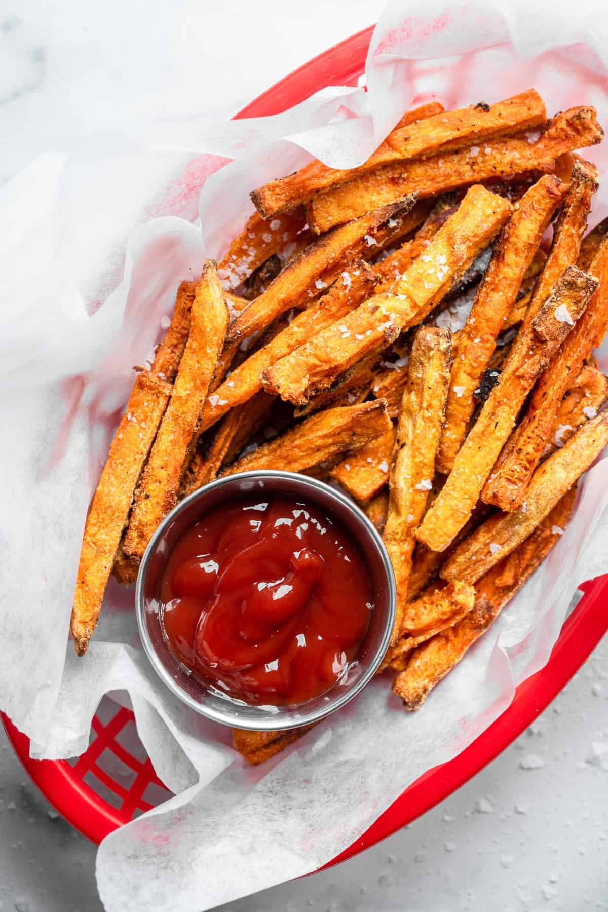 close up of baked sweet potato fries with seasoning and ketchup on the side