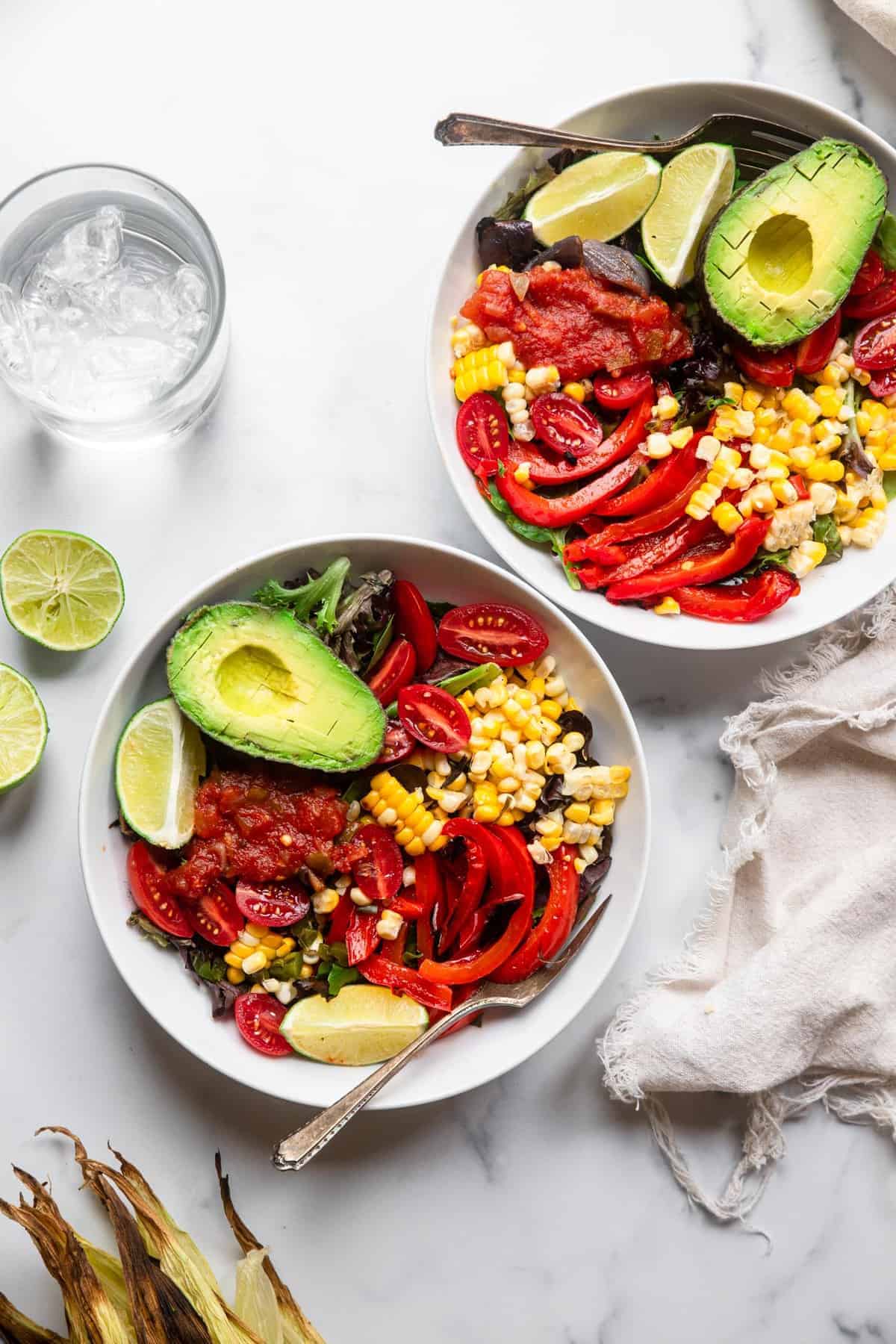 mexican grilled corn salad on a table with water and limes