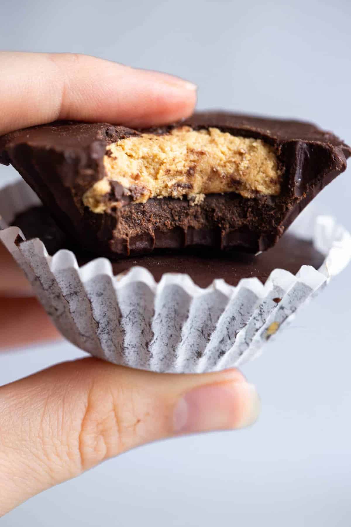 a hand holding chocolate peanut butter protein cups