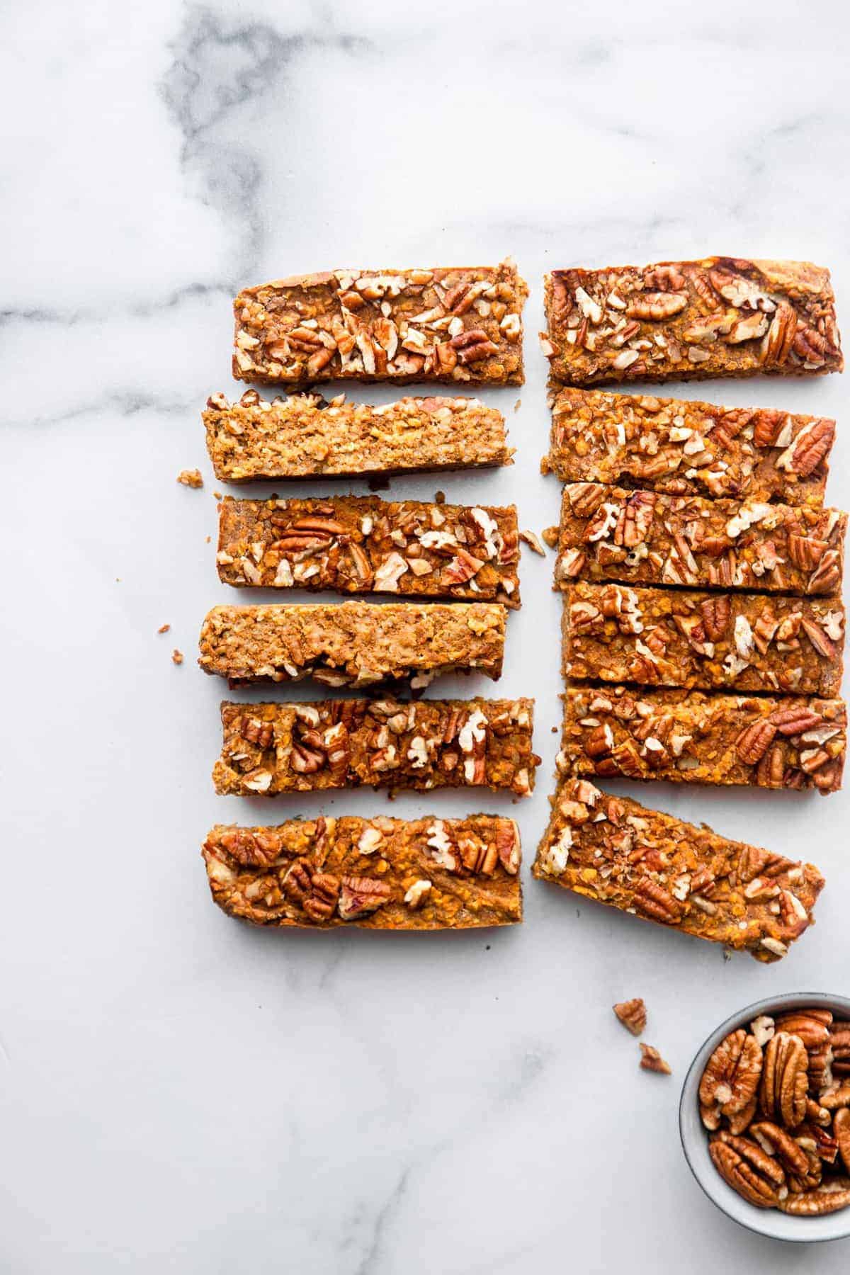 homemade pumpkin protein bars on a table with pecans on the side