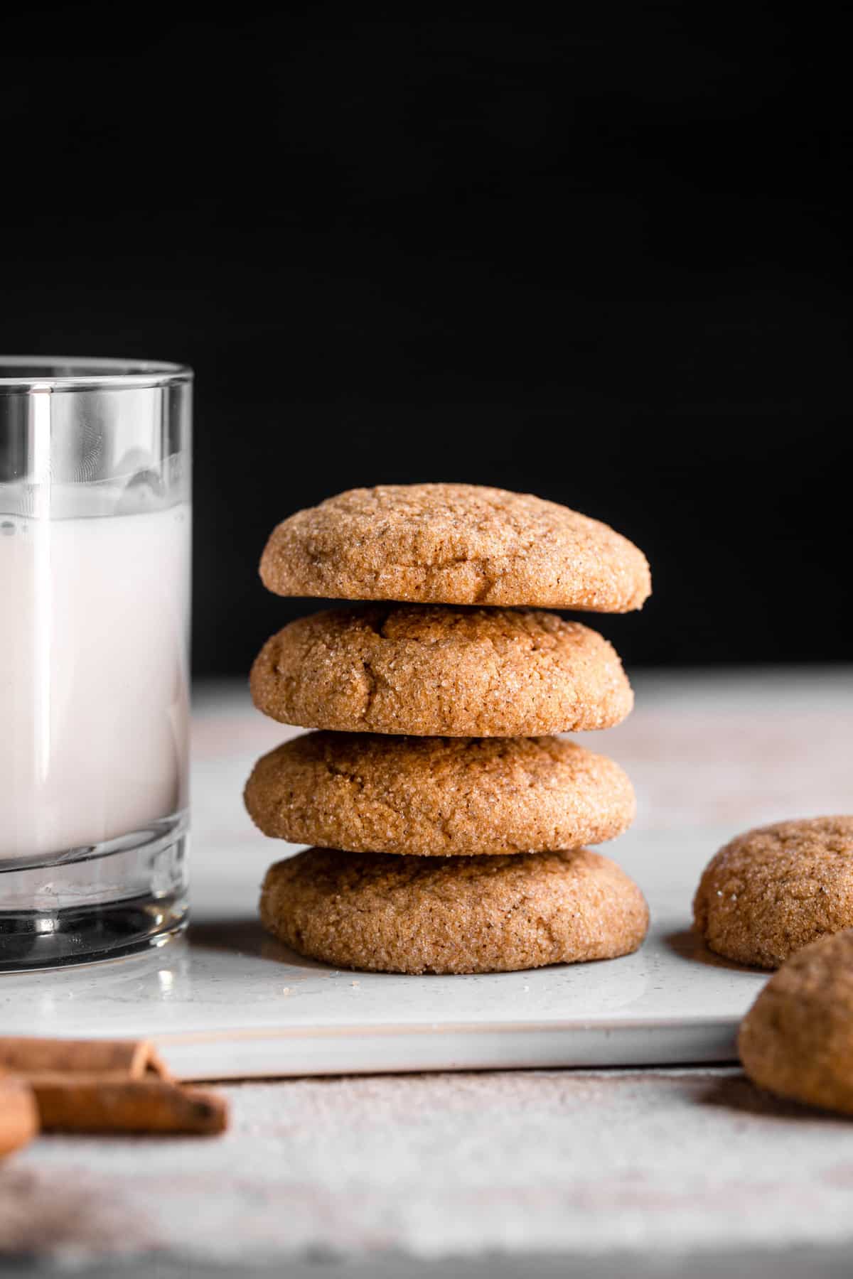 four stacked pumpkin sugar cookies with a glass of milk