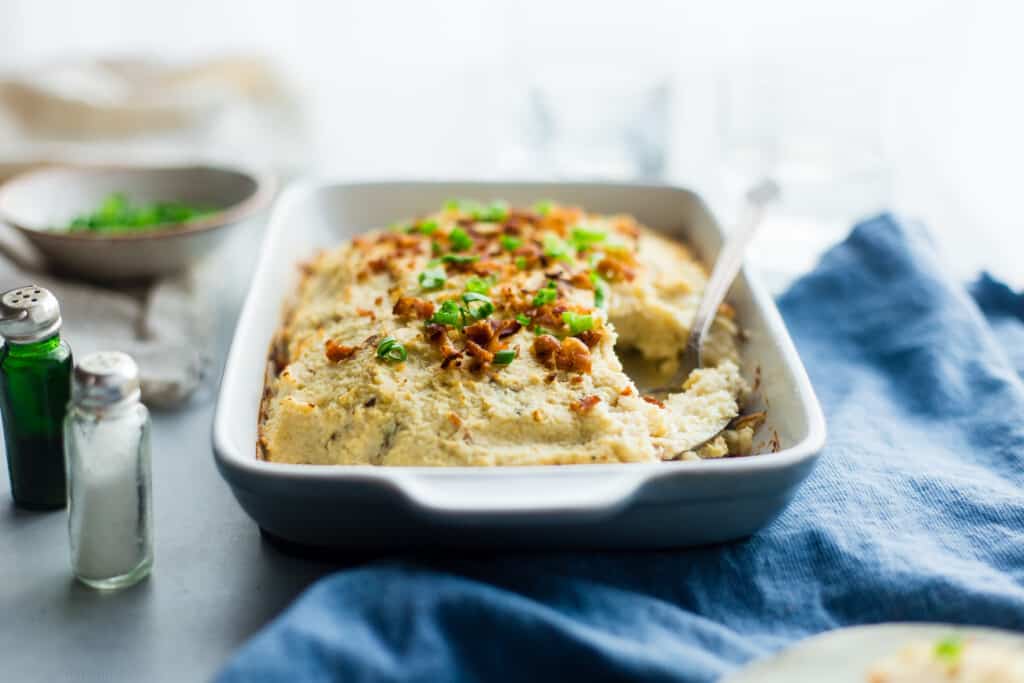 cauliflower bake in a casserole dish on a table with serving spoon