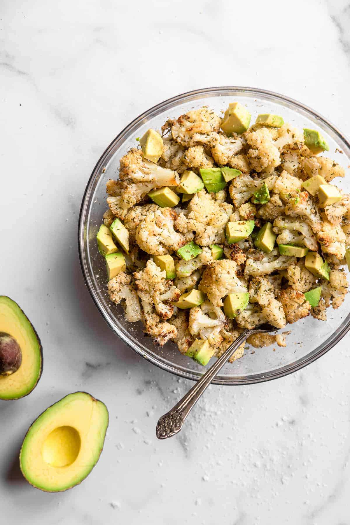 overhead view of ranch cauliflower in a bowl with avocado on the side