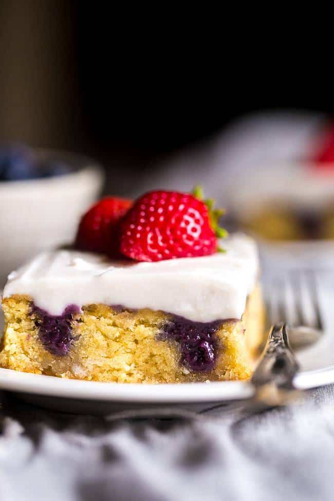 Paleo Poke Cake with Blueberries, Strawberries and Coconut Cream - The sweet pockets of homemade blueberry filling make this cake SO moist! It’s topped with whipped coconut cream and strawberries for an easy, healthier dessert that is perfect for July 4th! | Foodfaithfitness.com | @FoodFaithFit