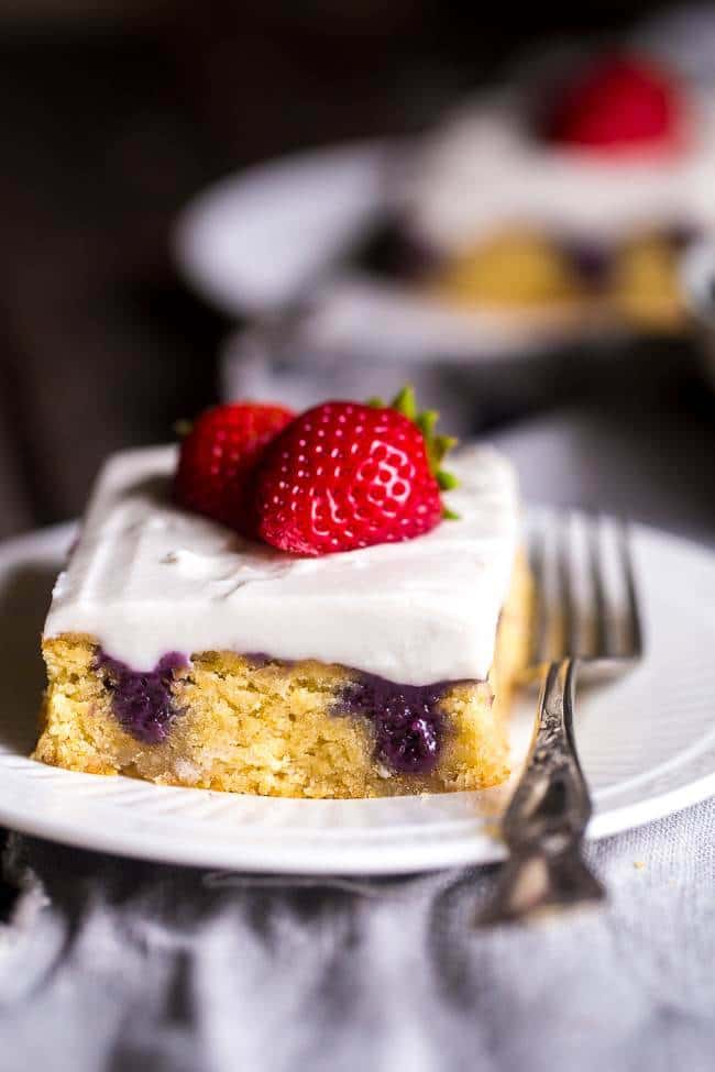Paleo Poke Cake with Blueberries, Strawberries and Coconut Cream - The sweet pockets of homemade blueberry filling make this cake SO moist! It’s topped with whipped coconut cream and strawberries for an easy, healthier dessert that is perfect for July 4th! | Foodfaithfitness.com | @FoodFaithFit
