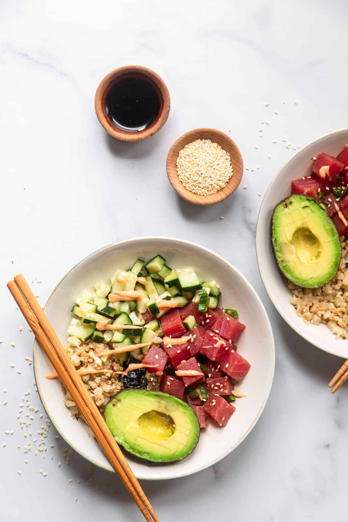 low carb poke bowl on a table with sesame seeds and sauce on the side