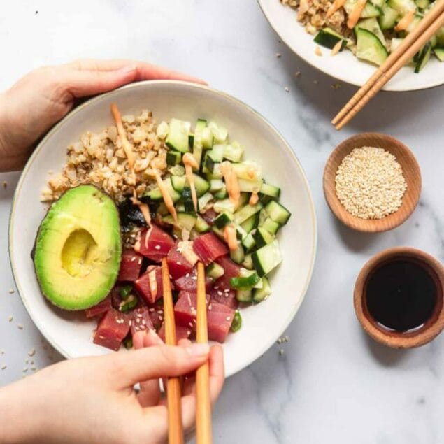 image of low carb poke bowl on a table being eaten with chopsticks