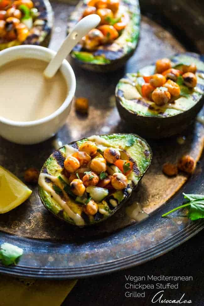 Vegan Mediterranean Chickpea Stuffed Grilled Avocado - Grilled avocado is stuffed with fresh cucumber, tomato and crispy grilled chickpeas! A drizzle of tahini makes this a delicious, healthy and easy, vegan dinner for under 250 calories! | Foodfaithfitness.com | @FoodFaithFit