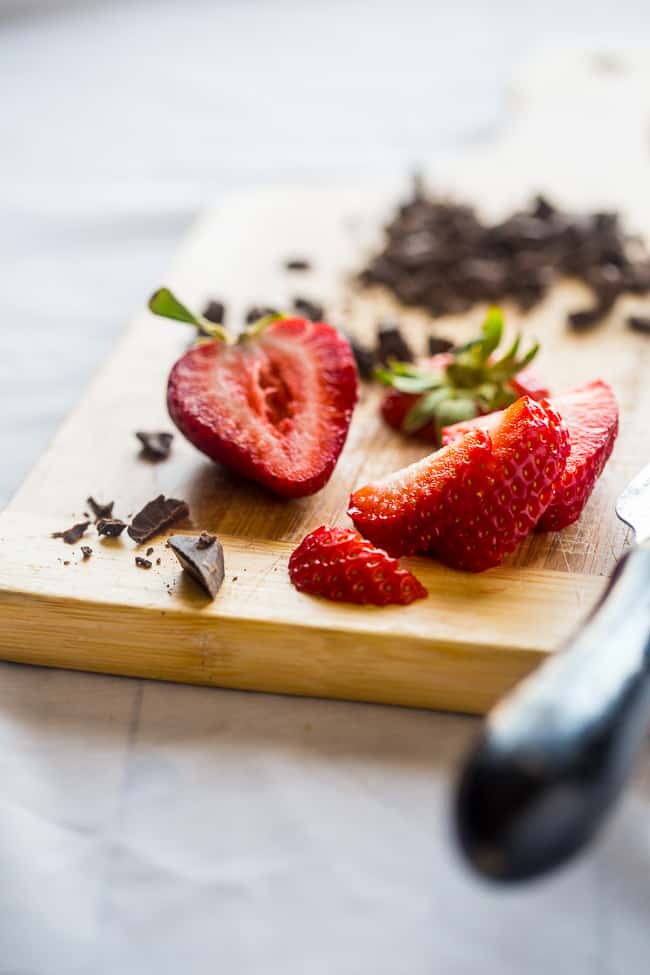 strawberries on a cutting board with chocolate for vegan smoothie bowl