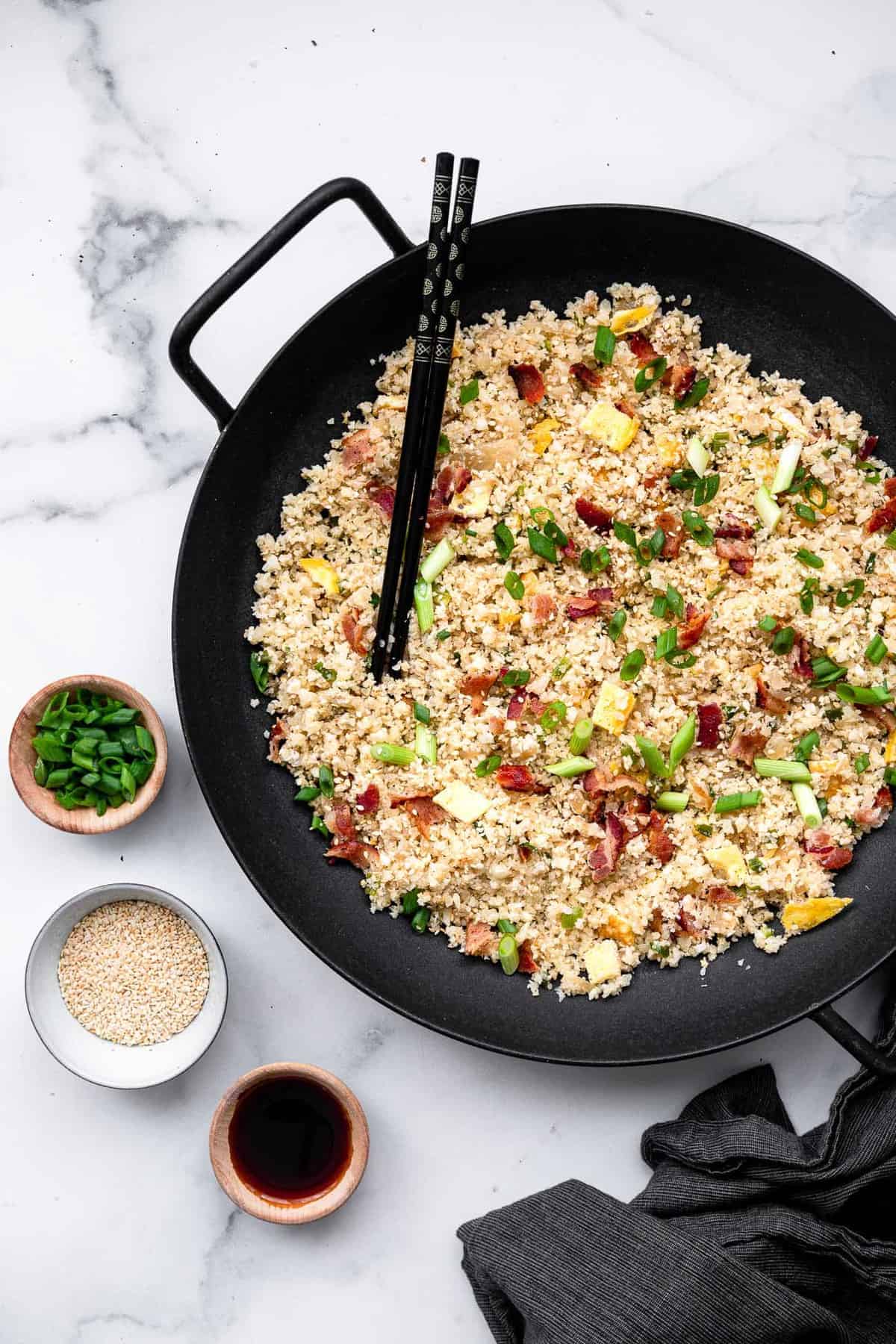 paleo fried rice in a wok with soy sauce on the side