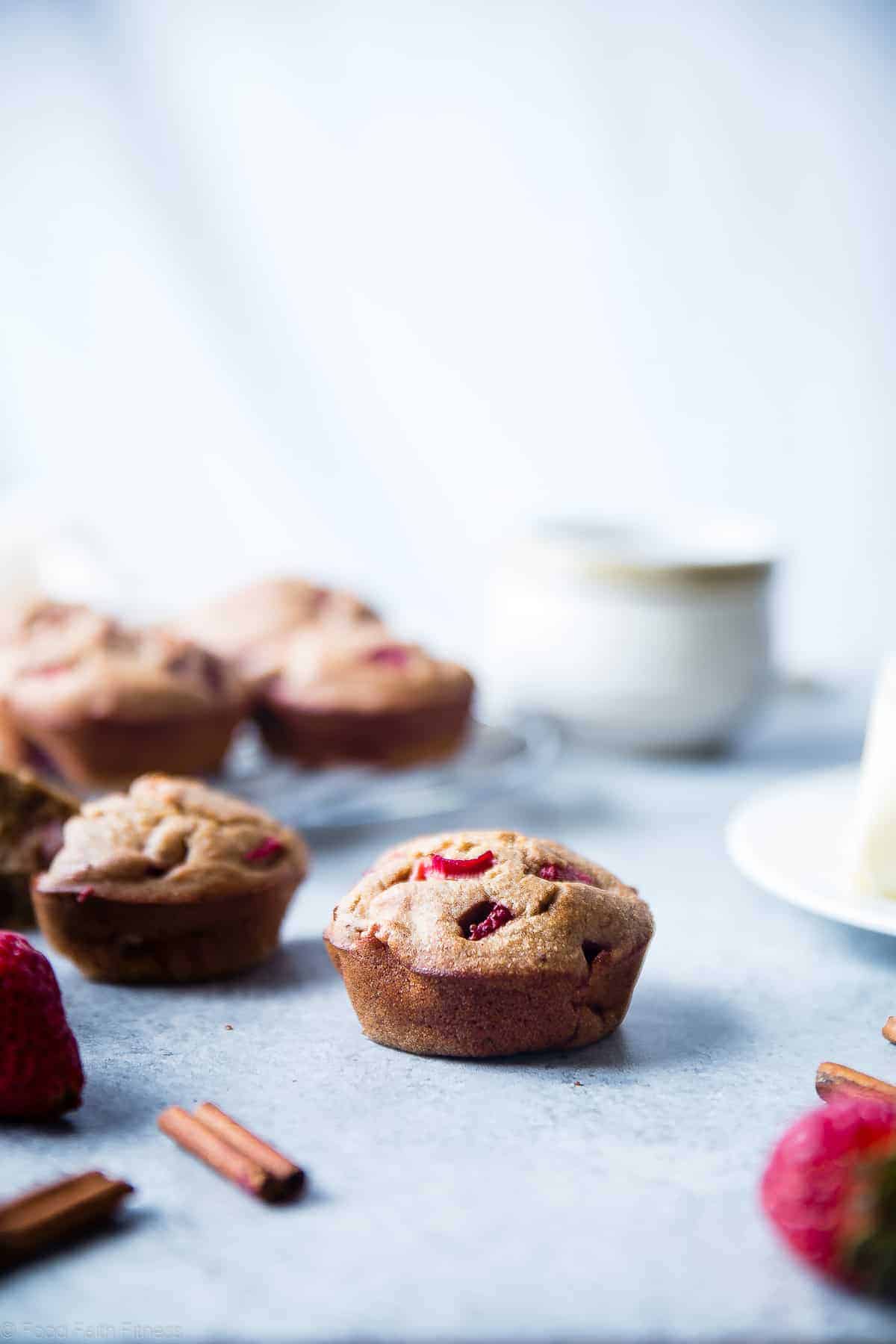 strawberry rhubarb muffins on a table with dishes