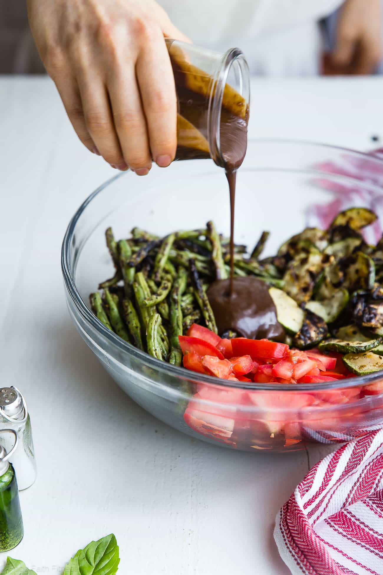 Pouring balsamic vinaigrette on grilled zucchini and green bean salad. Recipe on Foodfaithfitness.com