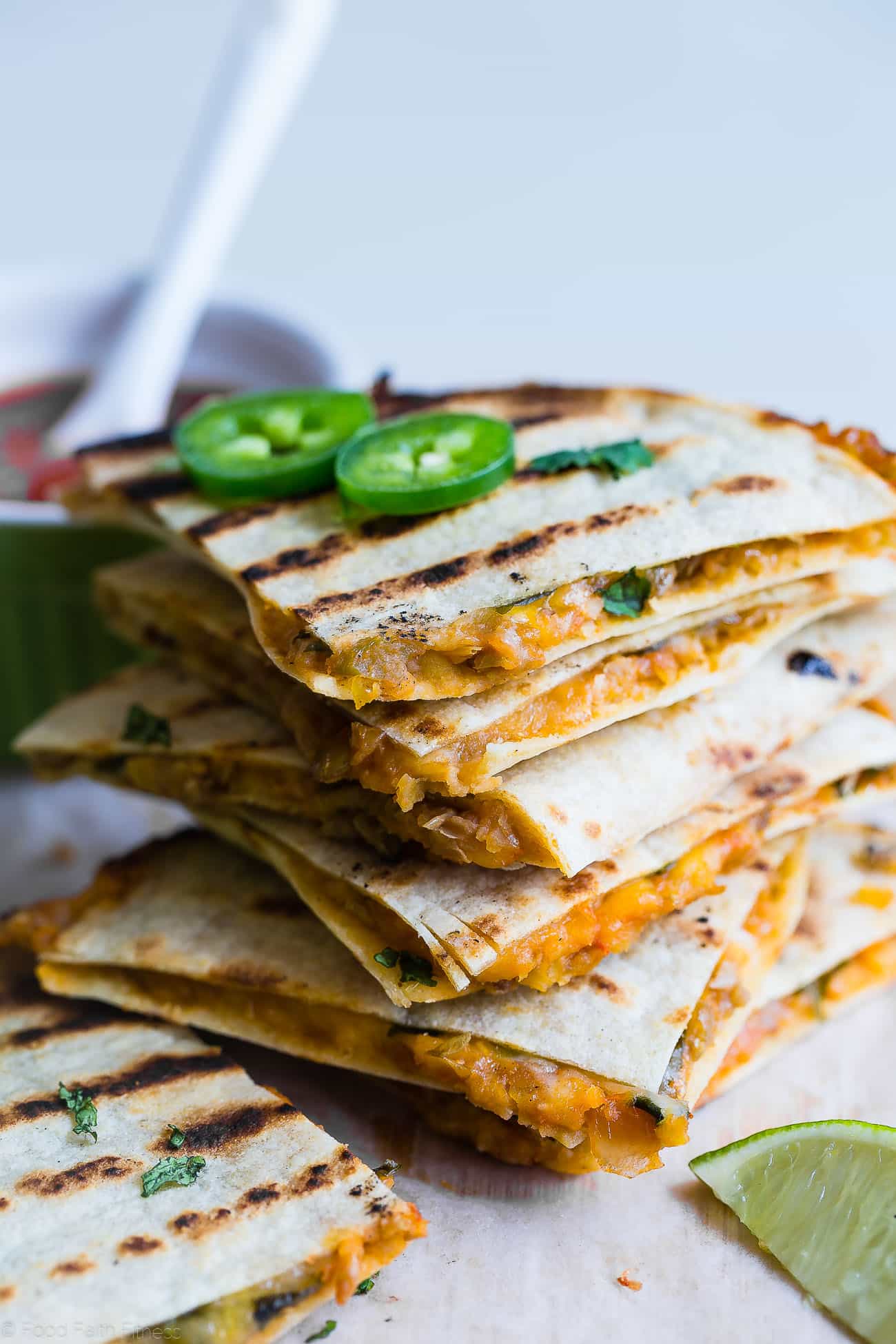 Close up shot of Grilled Mexican Lentil Quesadillas stacked on a cutting board. Recipe on Foodfaithfitness.com