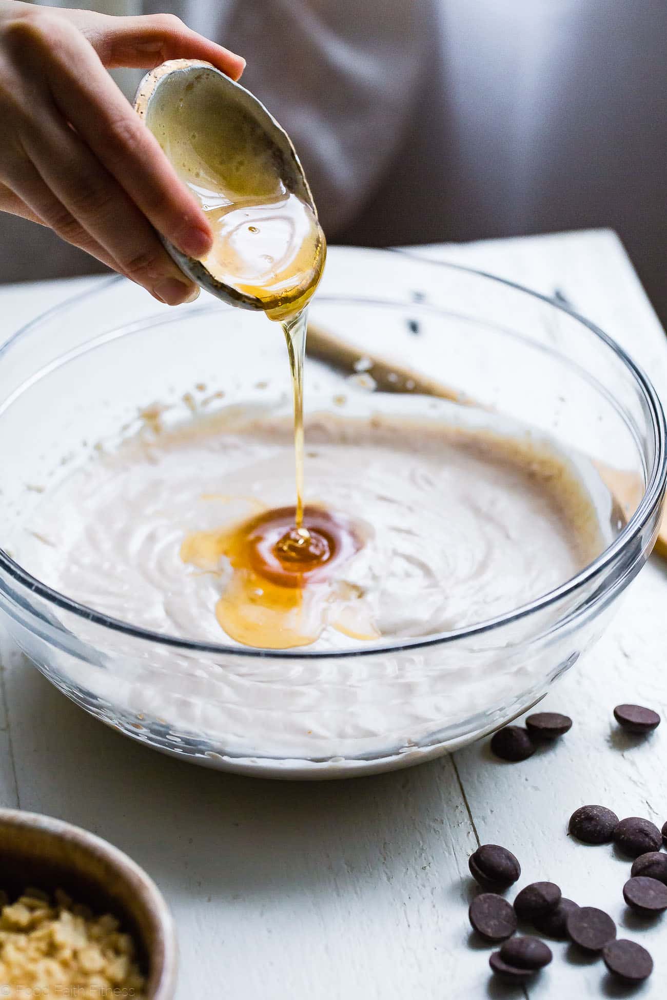 Pouring honey into a bowl of coconut cream. Recipe on Foodfaithfitness.com