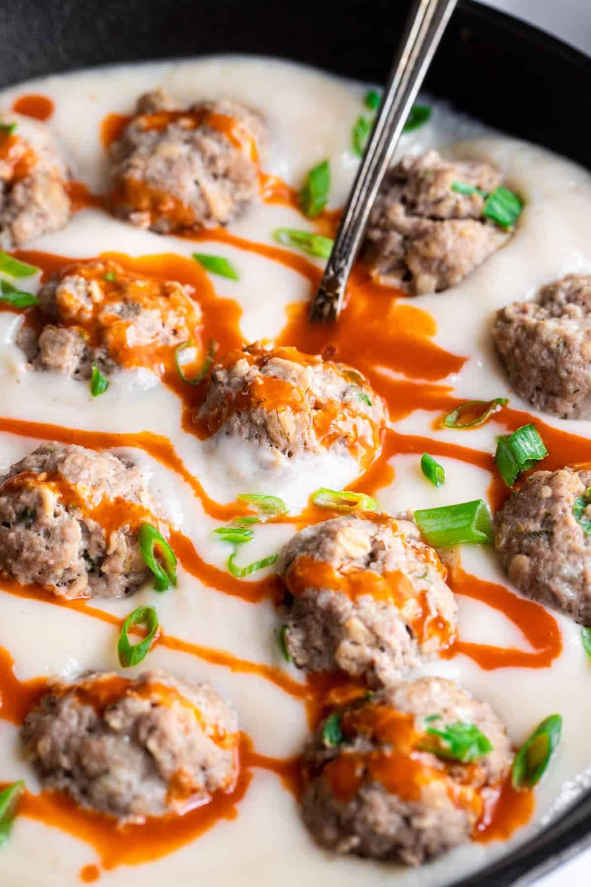 close up of low carb buffalo chicken meatballs in a cast iron skillet