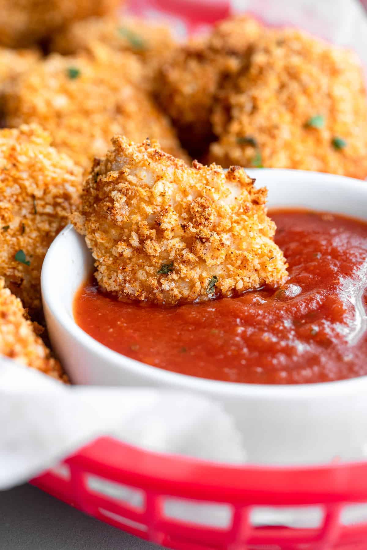 Air fryer chicken nuggets being dipped into ketchup