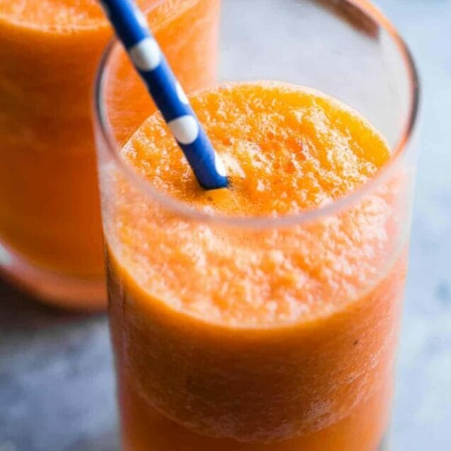 Orange Carrot Smoothie with Ginger in a glass with blue straw