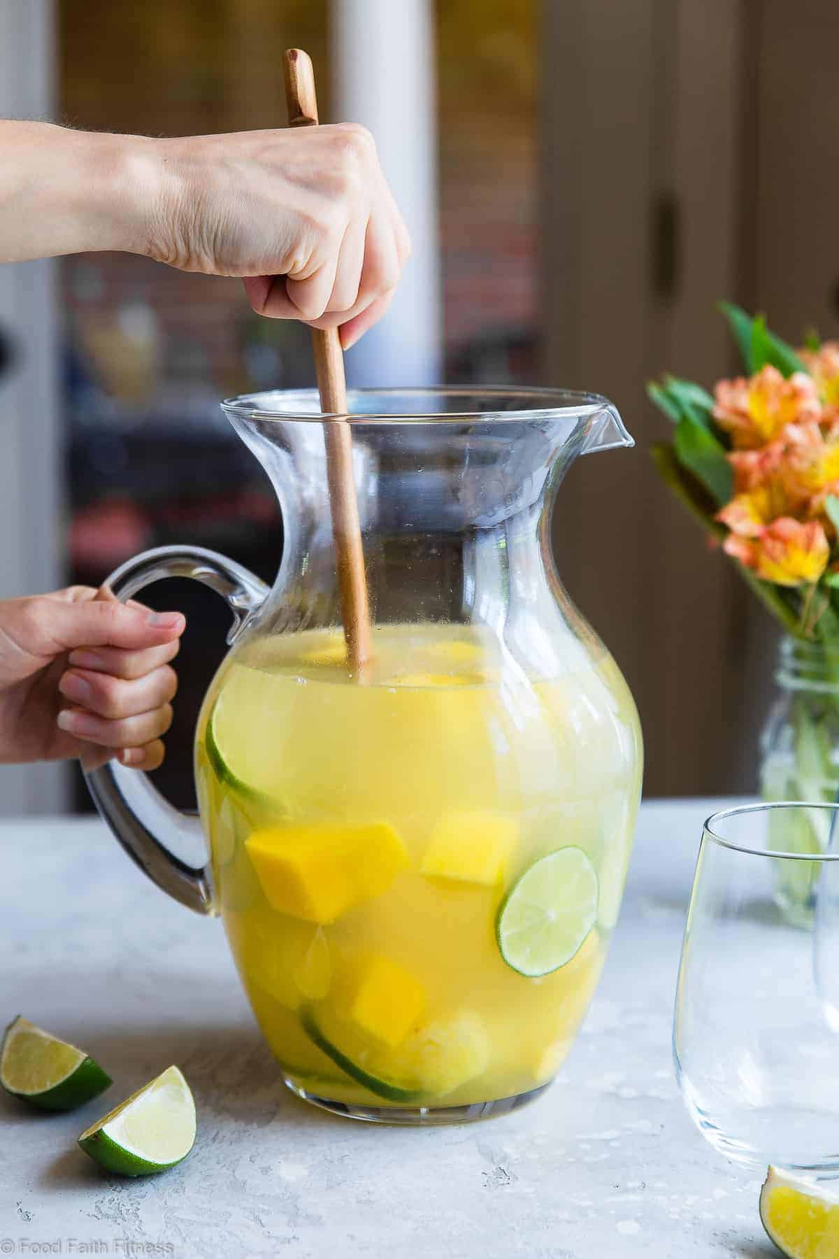 moscato sangria in a pitcher being stirred with a large spoon