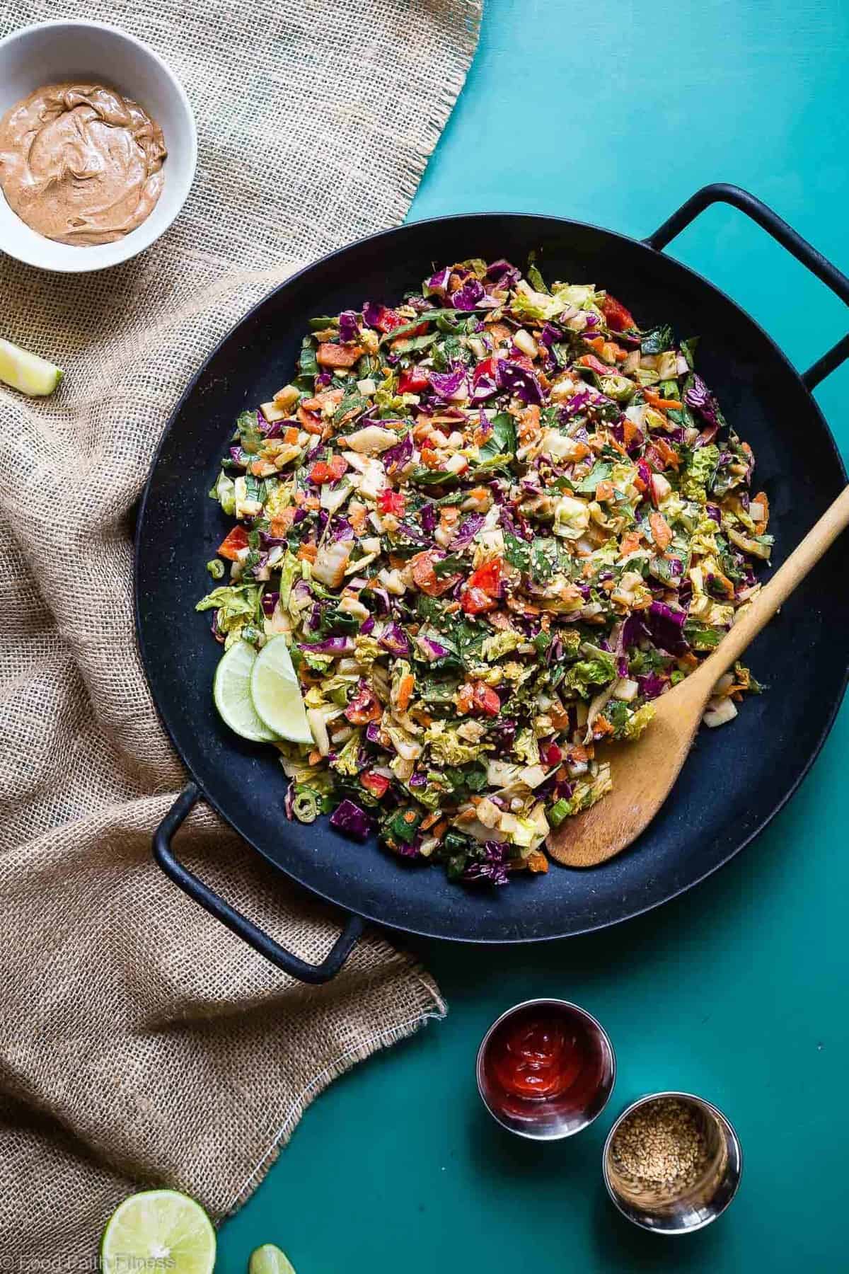 a large wok full of Oriental Coleslaw with a spoon