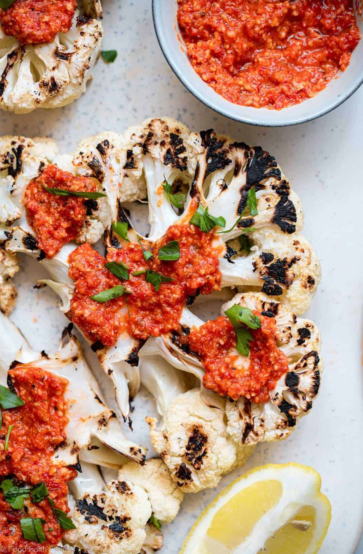 A close up of a grilled cauliflower steak with romesco sauce