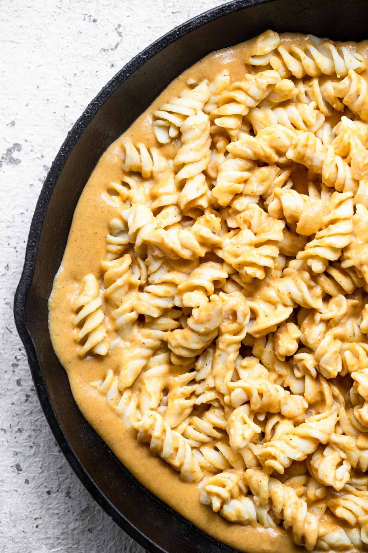 Noodles in a skillet full of creamy pumpkin pasta sauce