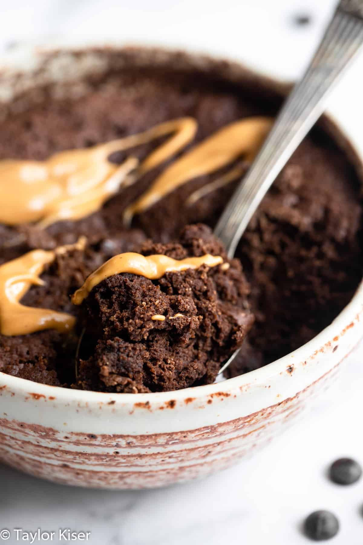 Chocolate keto mug cake with a spoon scooped into it