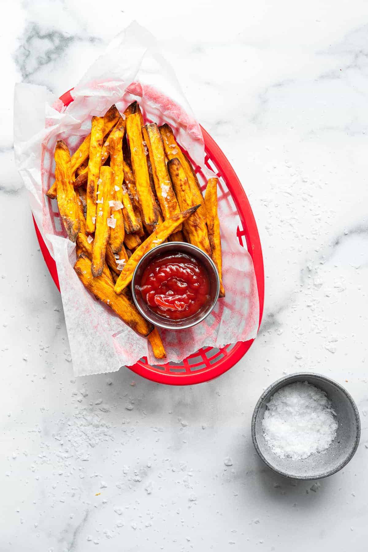 air fryer sweet potato fries in a basket with ketchup