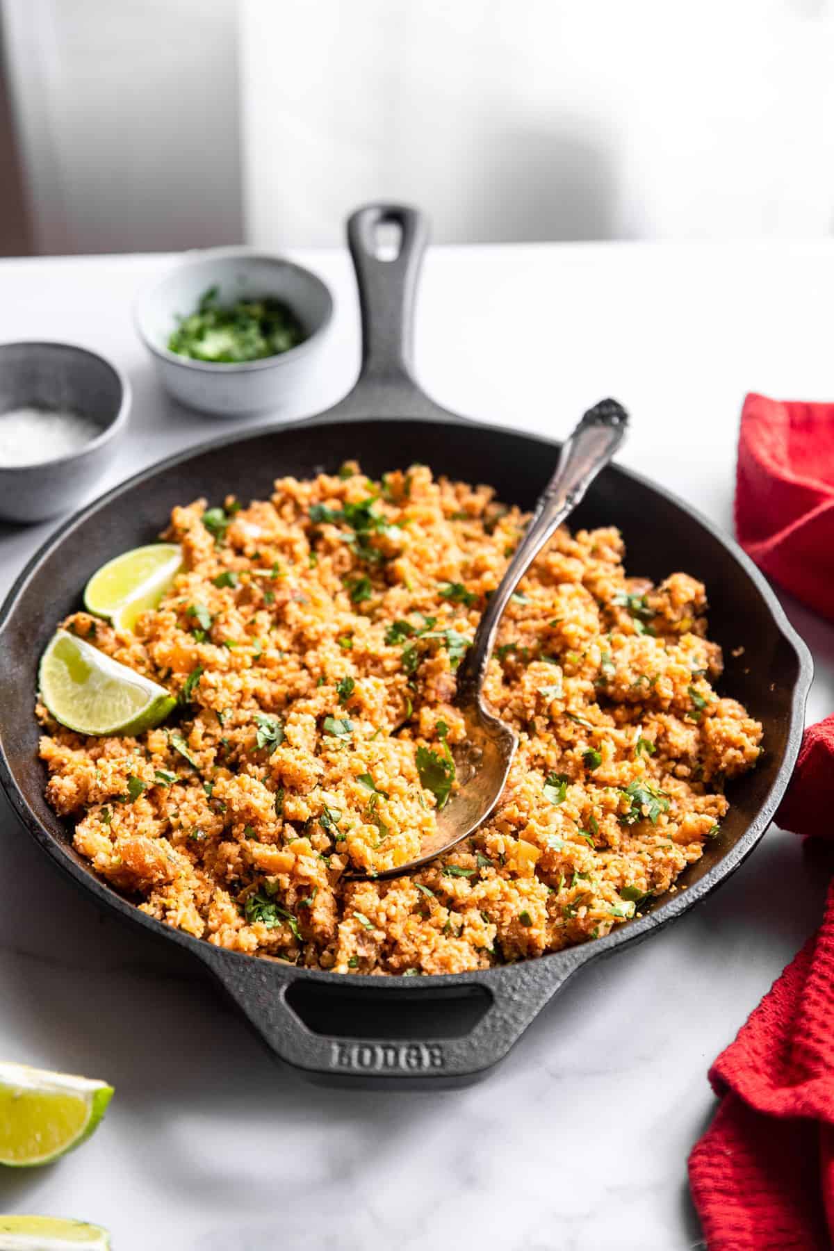 keto mexican cauliflower rice on a table with cilantro and limes