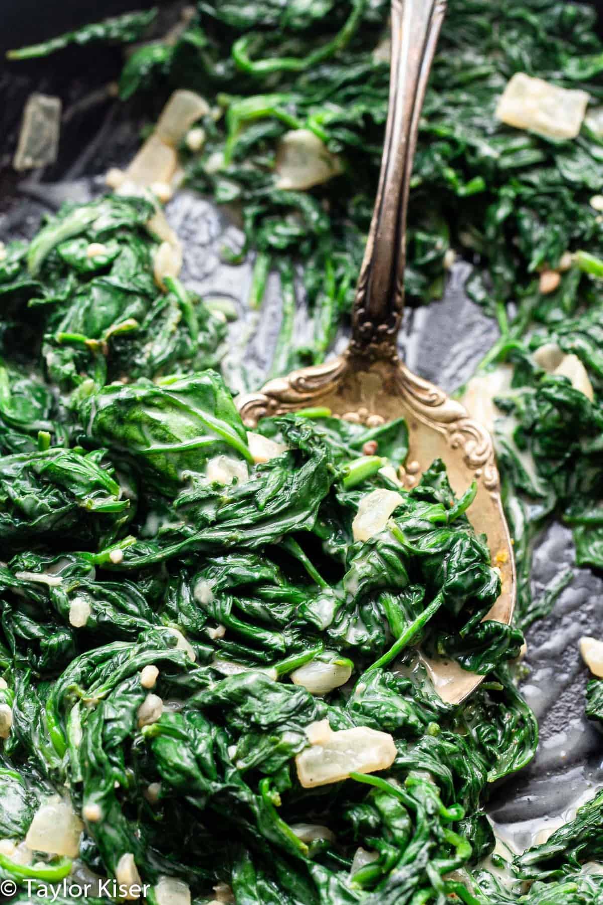 a spoon in a skillet of low carb keto creamed spinach