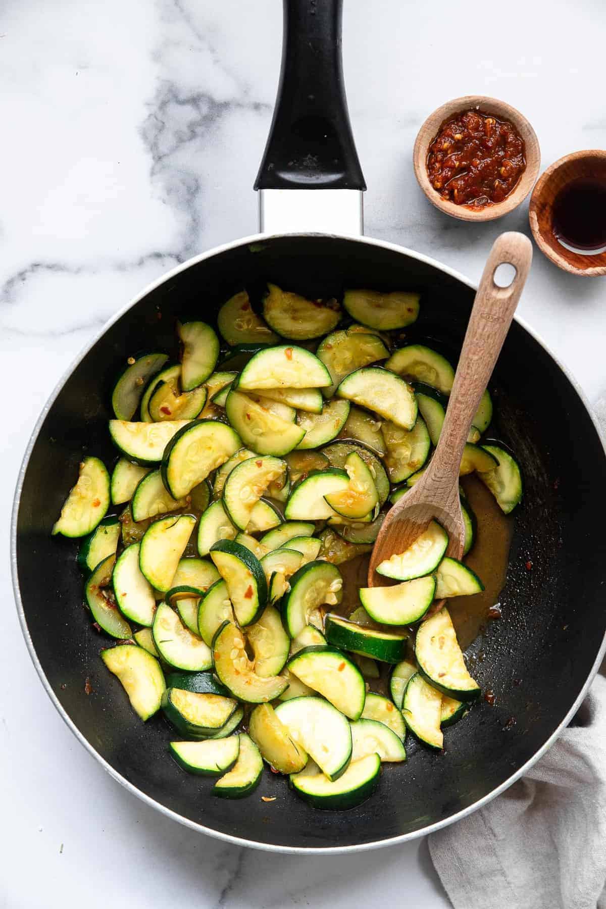 Zucchini Stir Fry in a giant fry pan with a wooden spoon
