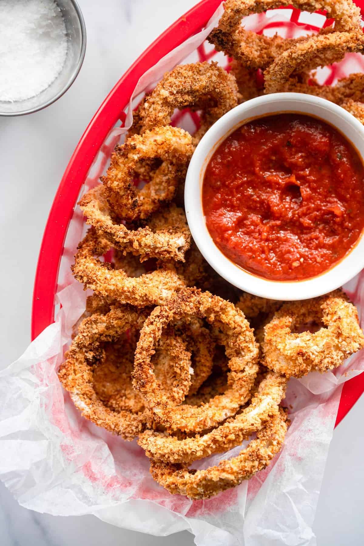 Air Fried Onion rings in a serving basket with dipping sauce