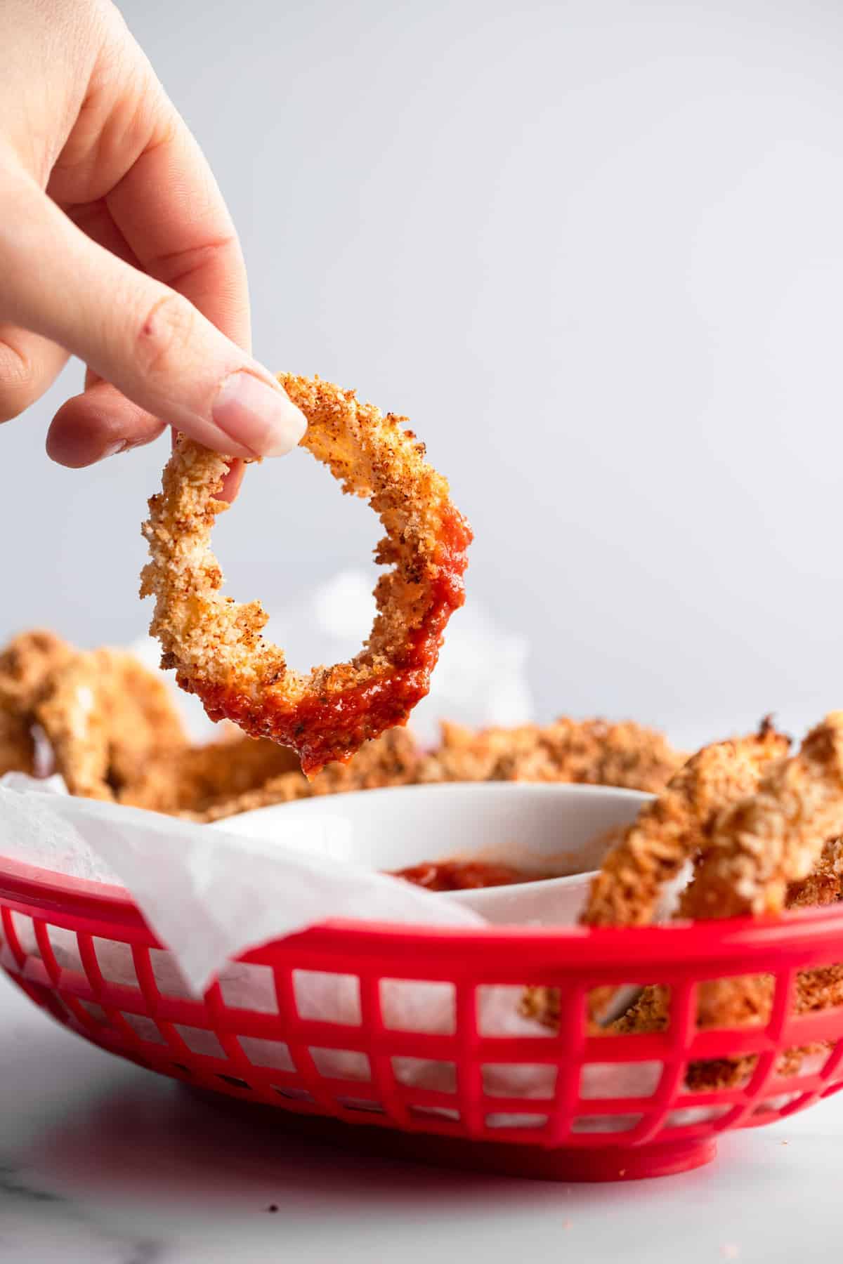 Recipe for onion rings dipped in sauce in a serving basket