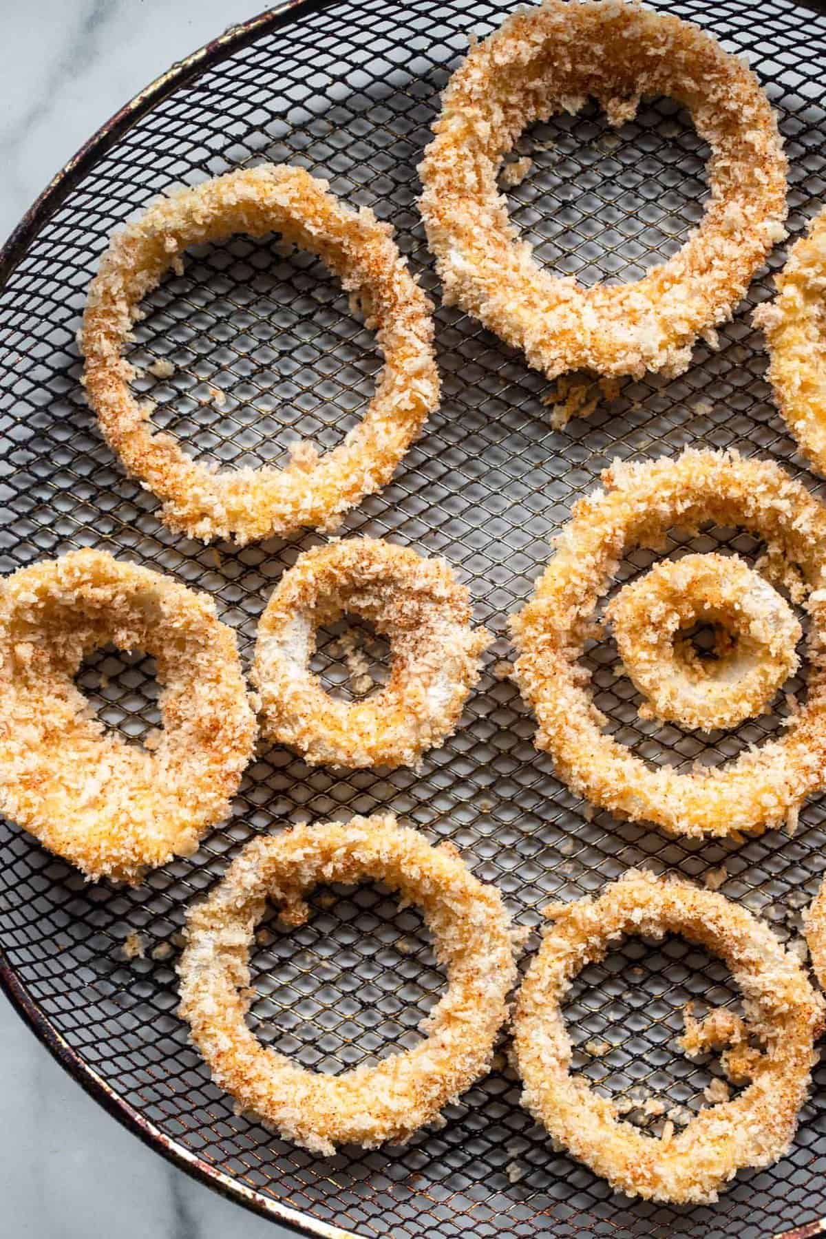 Onion rings air fryer on a mesh basket ready to be cooked