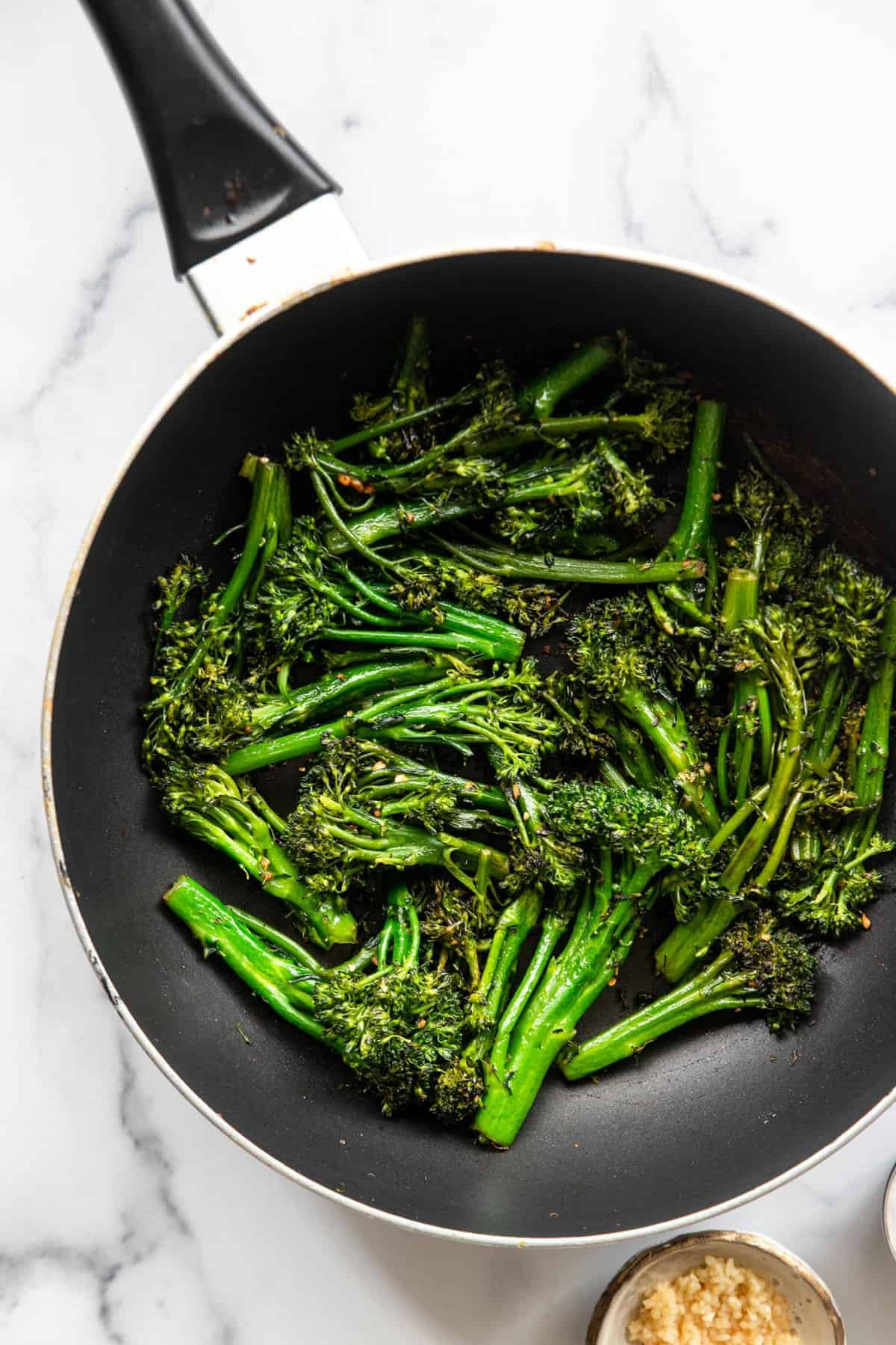 Sautéed broccolini in a pan being cooked
