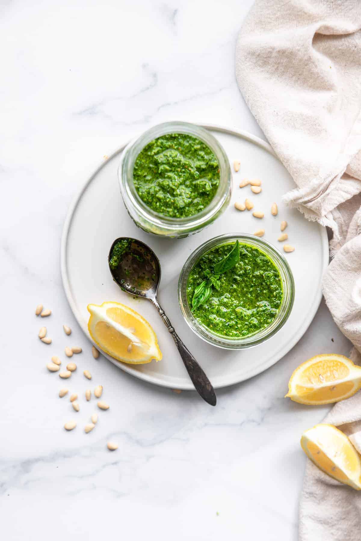 Spinach pesto sauce overview on a serving plate with lemon and a spoon