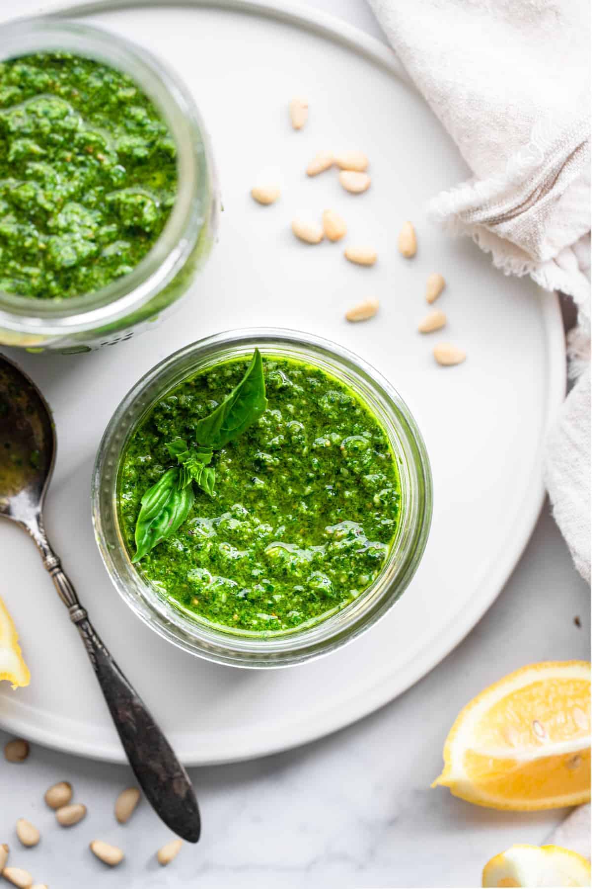 spinach pesto close up in a small jar with garnishes