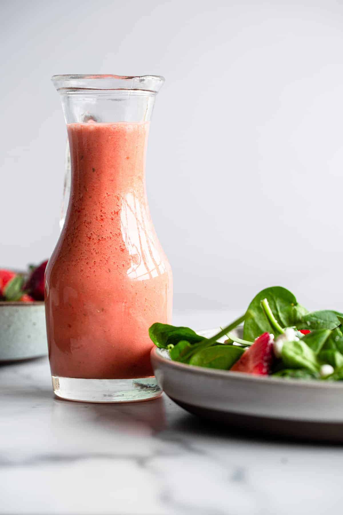 Strawberry Vinaigrette in a serving bottle with a salad