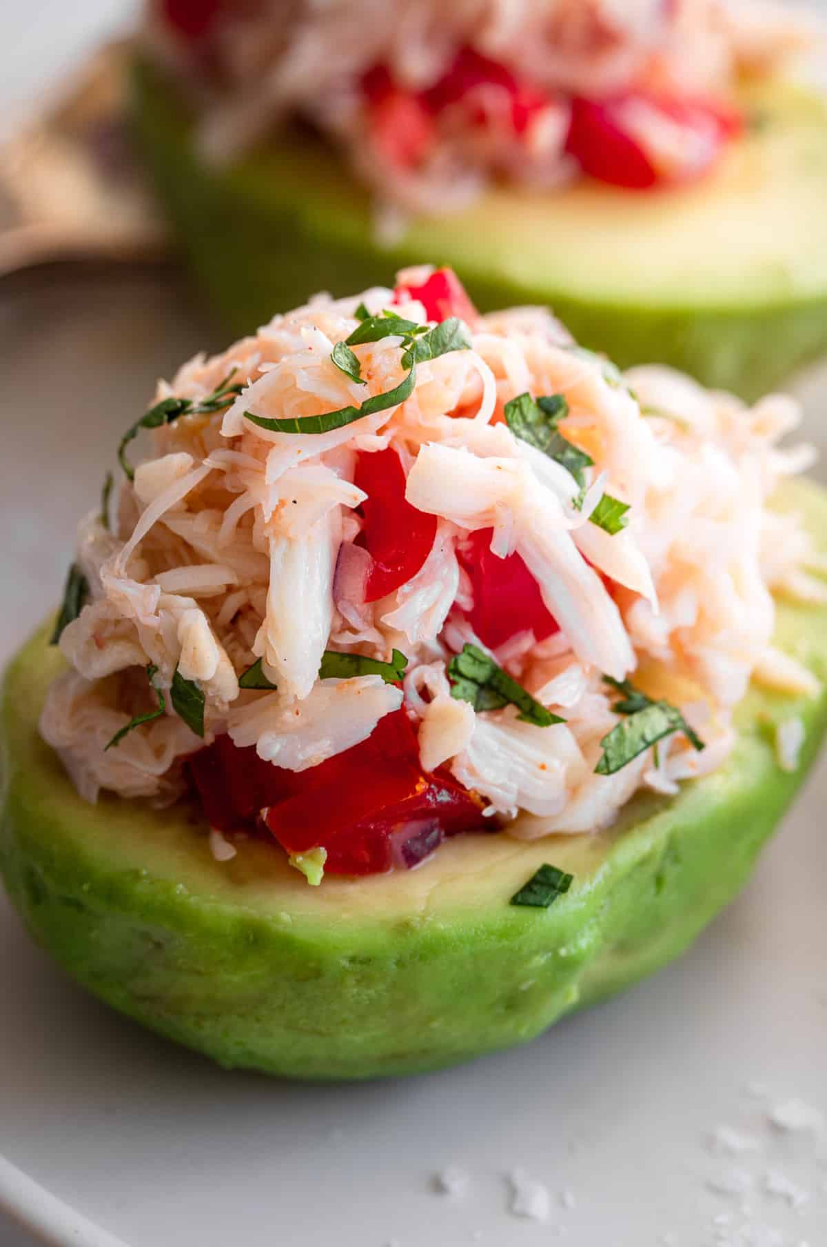 extreme close up of avocado with crab salad stuffed inside with cilantro topping