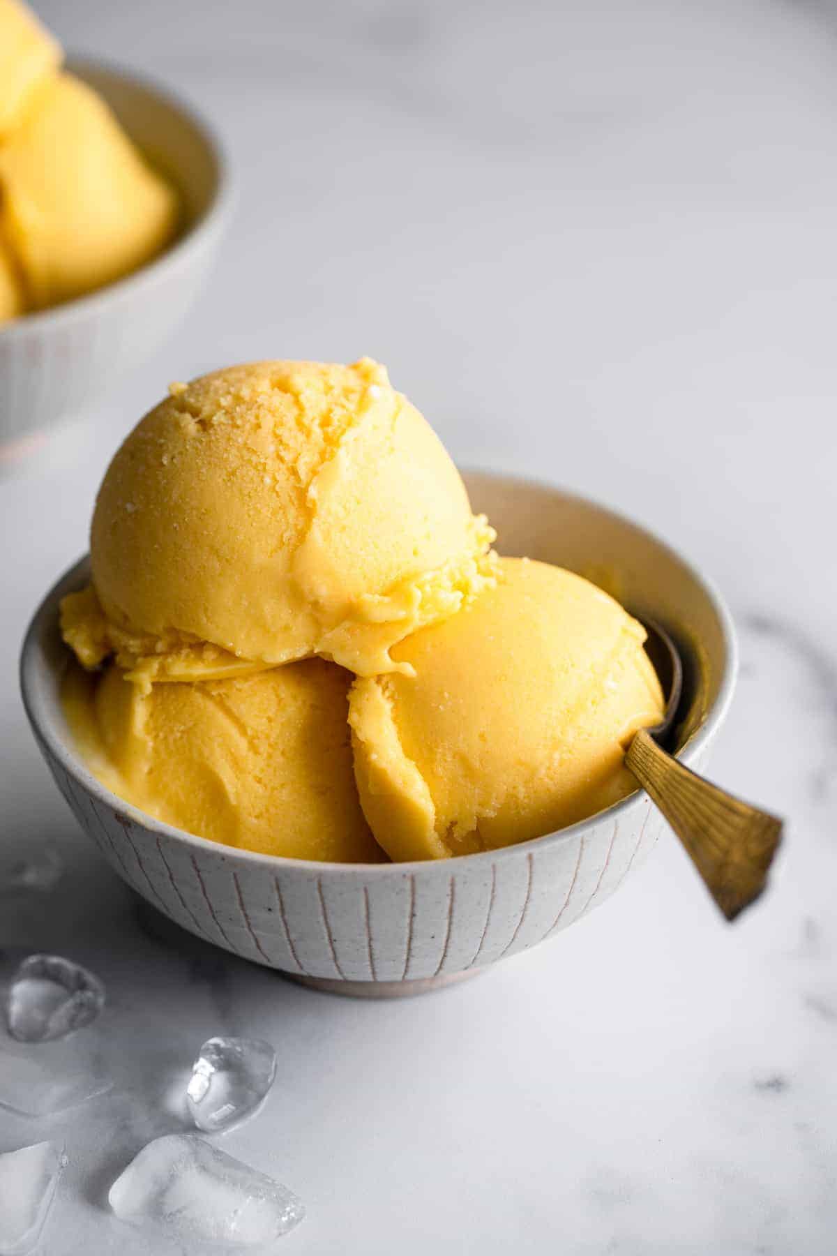 Mango frozen yogurt close up picture in a bowl with a spoon