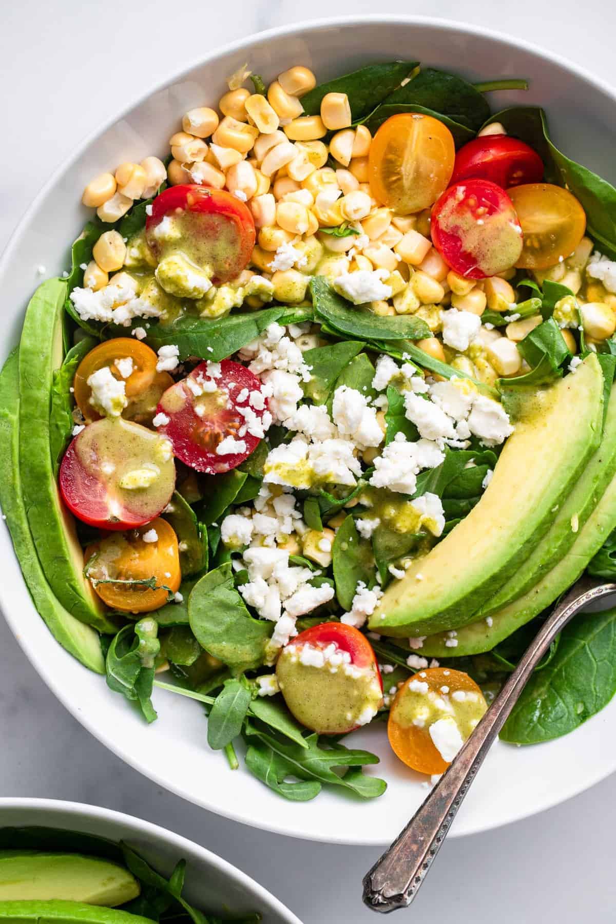 close up view of corn feta salad in a bowl with a spoon