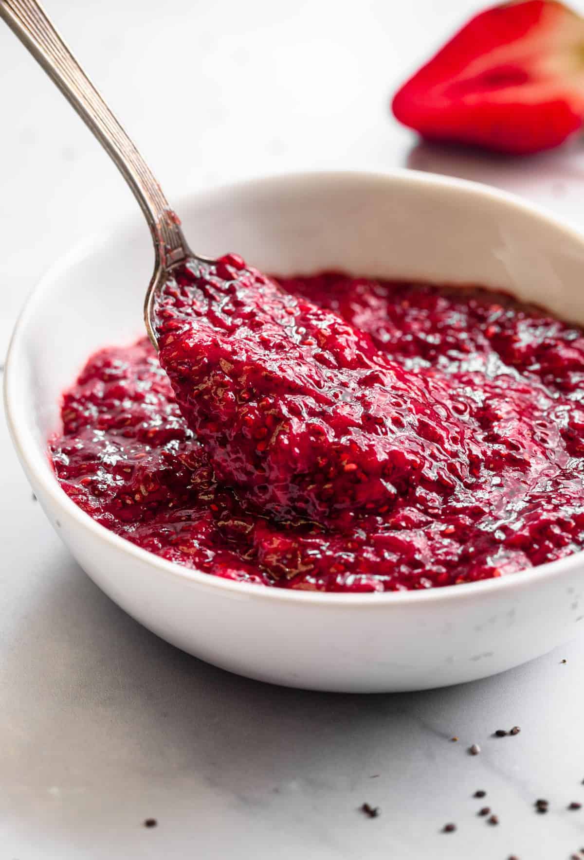 close up side view of strawberry chia jam in a bowl with spoon