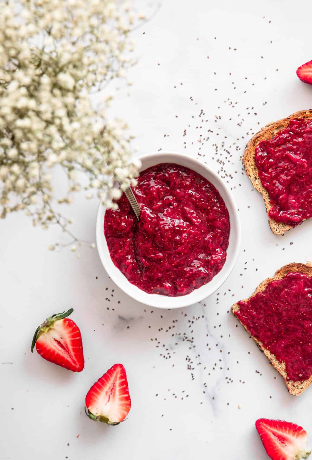 strawberry chia jam in a bowl with toast and strawberries on the side
