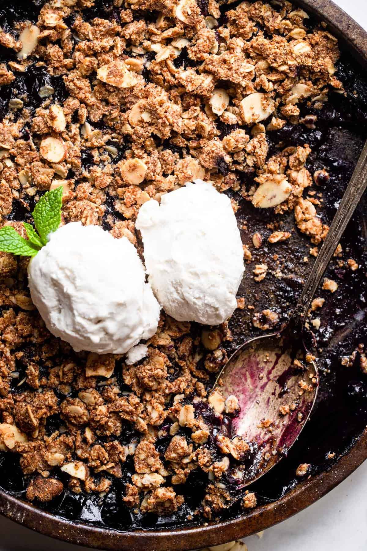Gluten Free Blueberry Crisp with ice cream on top and a spoon