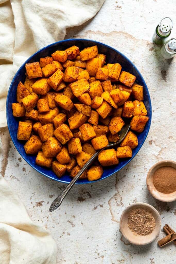 air fryer butternut squash in a blue bowl on a table with spices