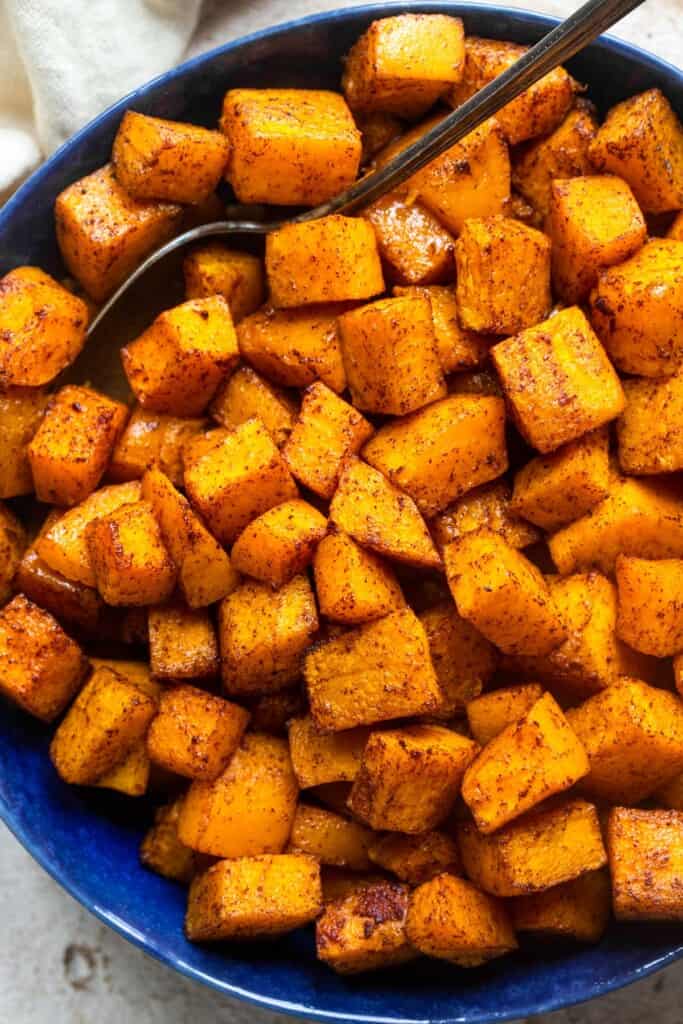 close up view of air fryer butternut squash in a blue bowl with a fork