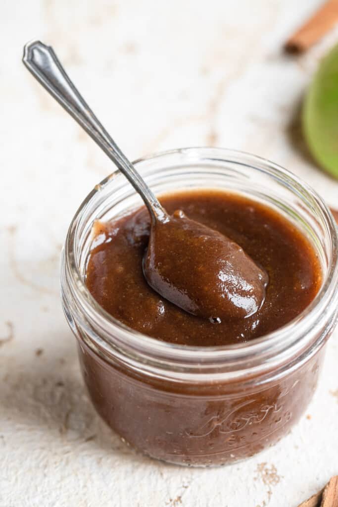 a spoon scooping instant pot apple butter out of a small jar